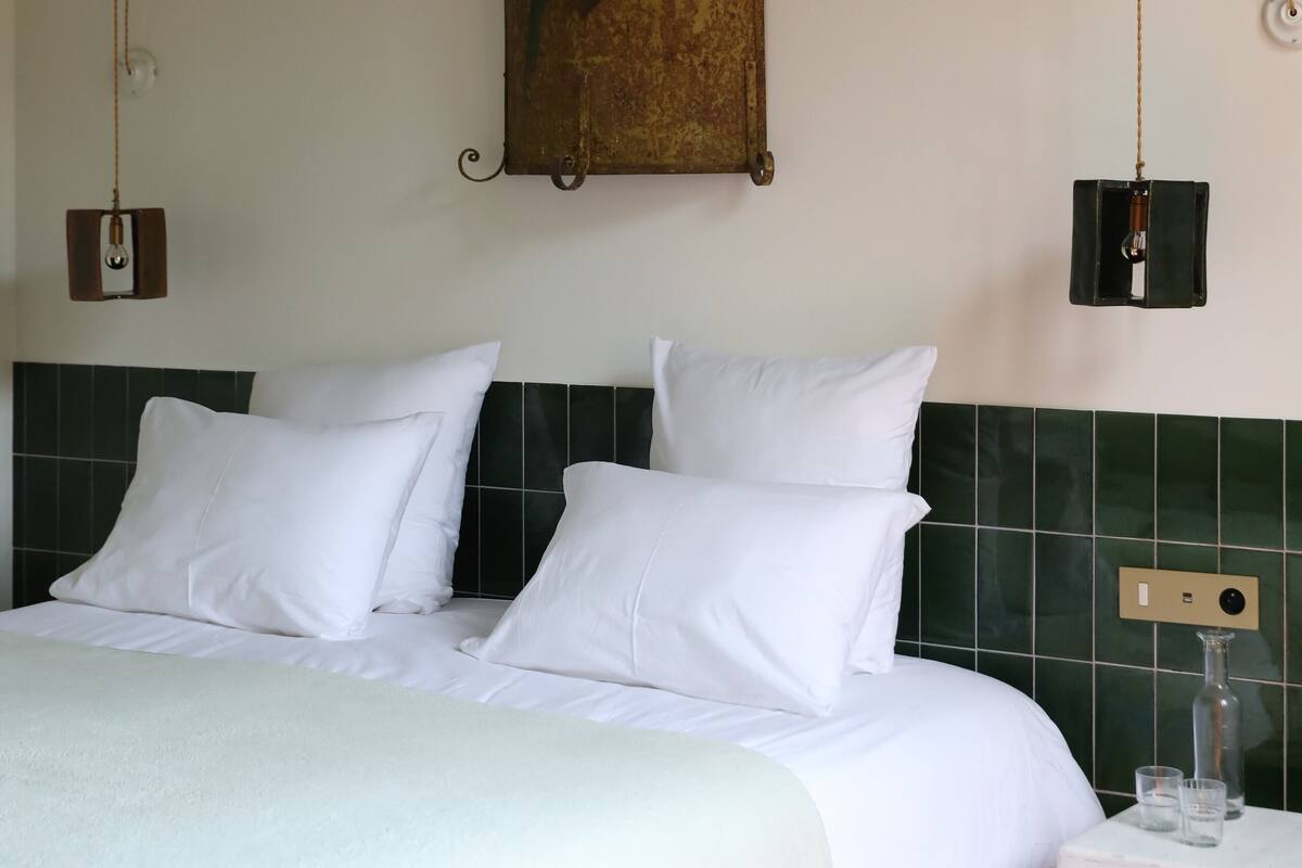 A hotel room with a bed, a nightstand, and a wall-mounted painting.