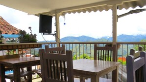 A covered outdoor seating area with tables and chairs, overlooking a mountainous landscape. - Casa Fibonacci (Titiribí)