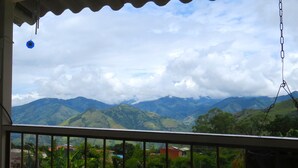 A view from a window overlooking a mountainous landscape with greenery and a few buildings in the foreground. - Casa Fibonacci (Titiribí)