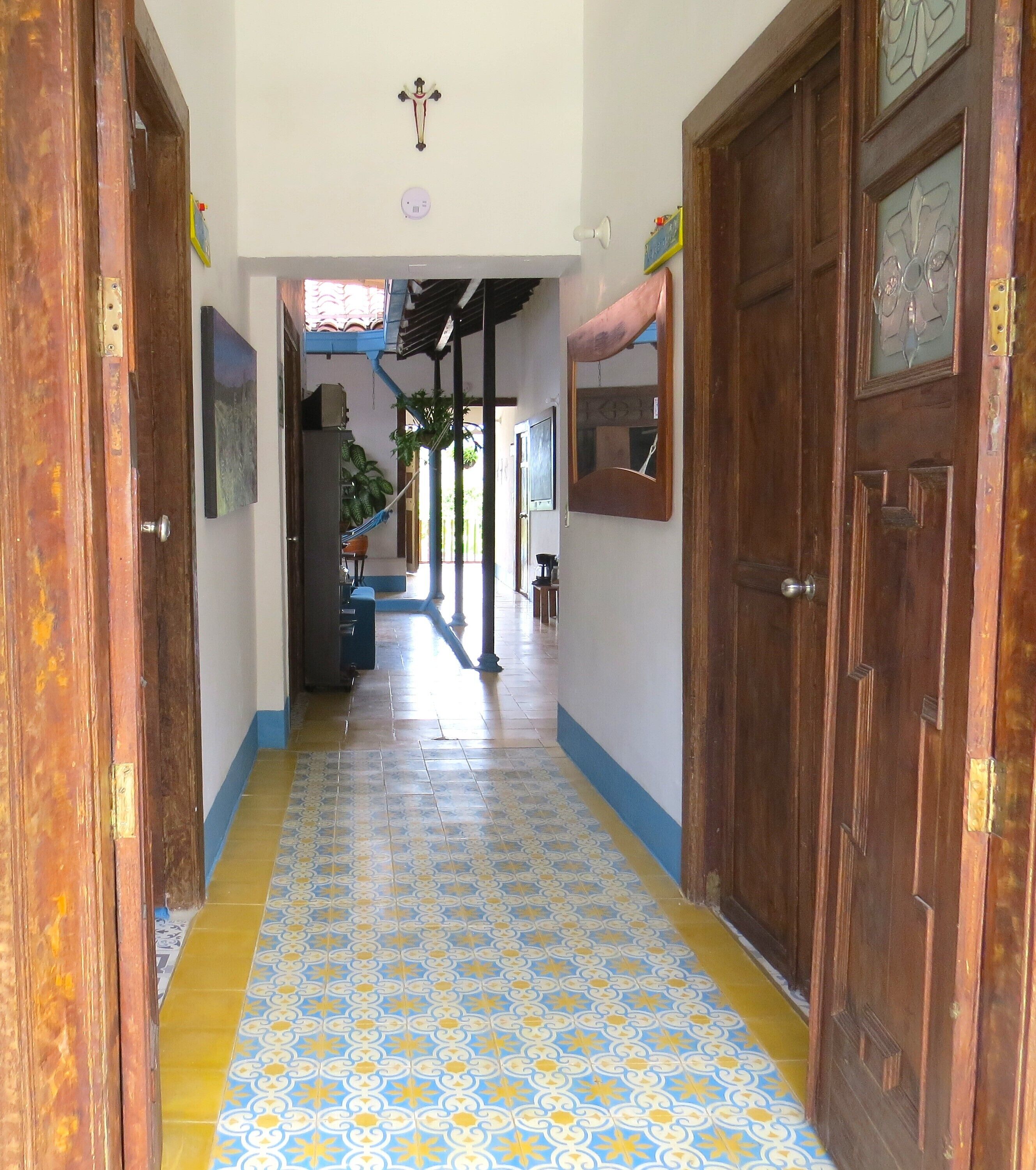 A hallway with patterned floor tiles, wooden doors, and a ceiling-mounted light fixture.