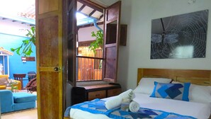 A bedroom with a bed, pillows, a wall-mounted artwork, and a door leading to another room. - Casa Fibonacci (Titiribí)