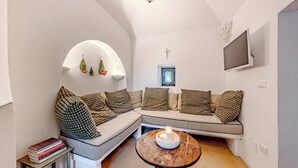 A cozy living room with a sectional sofa, a small coffee table, and a TV mounted on the wall. - Casale di Amelì 5, Emma Villas (Ostuni)