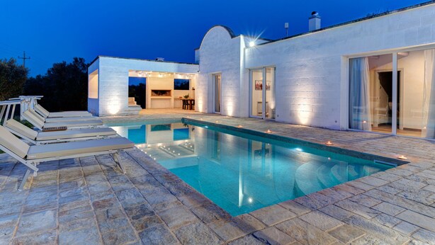 A modern house with a swimming pool, outdoor seating, and a barbecue area.