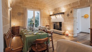 A dining area with a stone wall, a fireplace, and a table set for a meal.