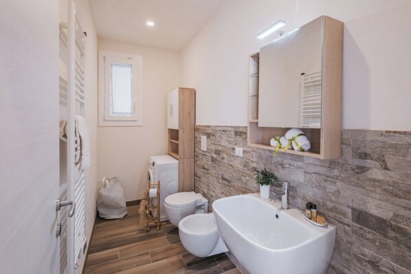 Un baño moderno con una bañera independiente, inodoro y lavadora.