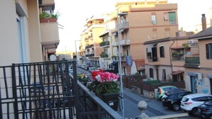 A residential street with multi-story buildings, balconies, and parked cars.