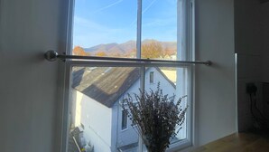 Une pièce dotée d’une grande fenêtre donnant sur une maison et des montagnes.