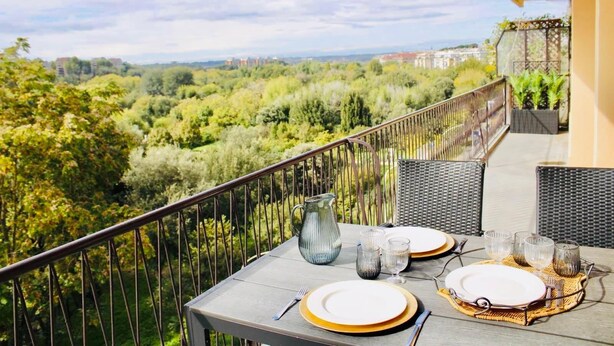 A balcony with a table set for dining, overlooking a lush landscape. - Penthouse in the center of Rome, with terrace a few meters from the Conca d'oro Metro.  (Roma)