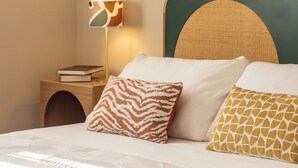 A neatly made bed with three pillows, a bedside lamp, and a wooden nightstand with a book. - Penthouse in the center of Rome, with terrace a few meters from the Conca d'oro Metro.  (Roma)