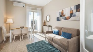A modern living room with a beige sofa, a dining table with chairs, a lamp, and a large abstract painting on the wall. - Penthouse in the center of Rome, with terrace a few meters from the Conca d'oro Metro.  (Roma)