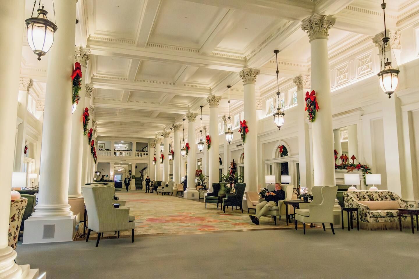 A spacious lobby with high ceilings, large columns, and chandeliers.