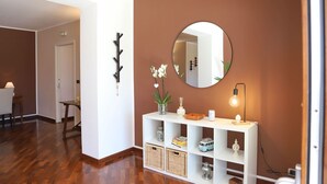 A hallway with a white console table, a round mirror, and a wall-mounted light fixture.