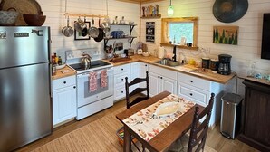 Una cocina con armarios blancos, una mesa de madera y un colgador para ollas.