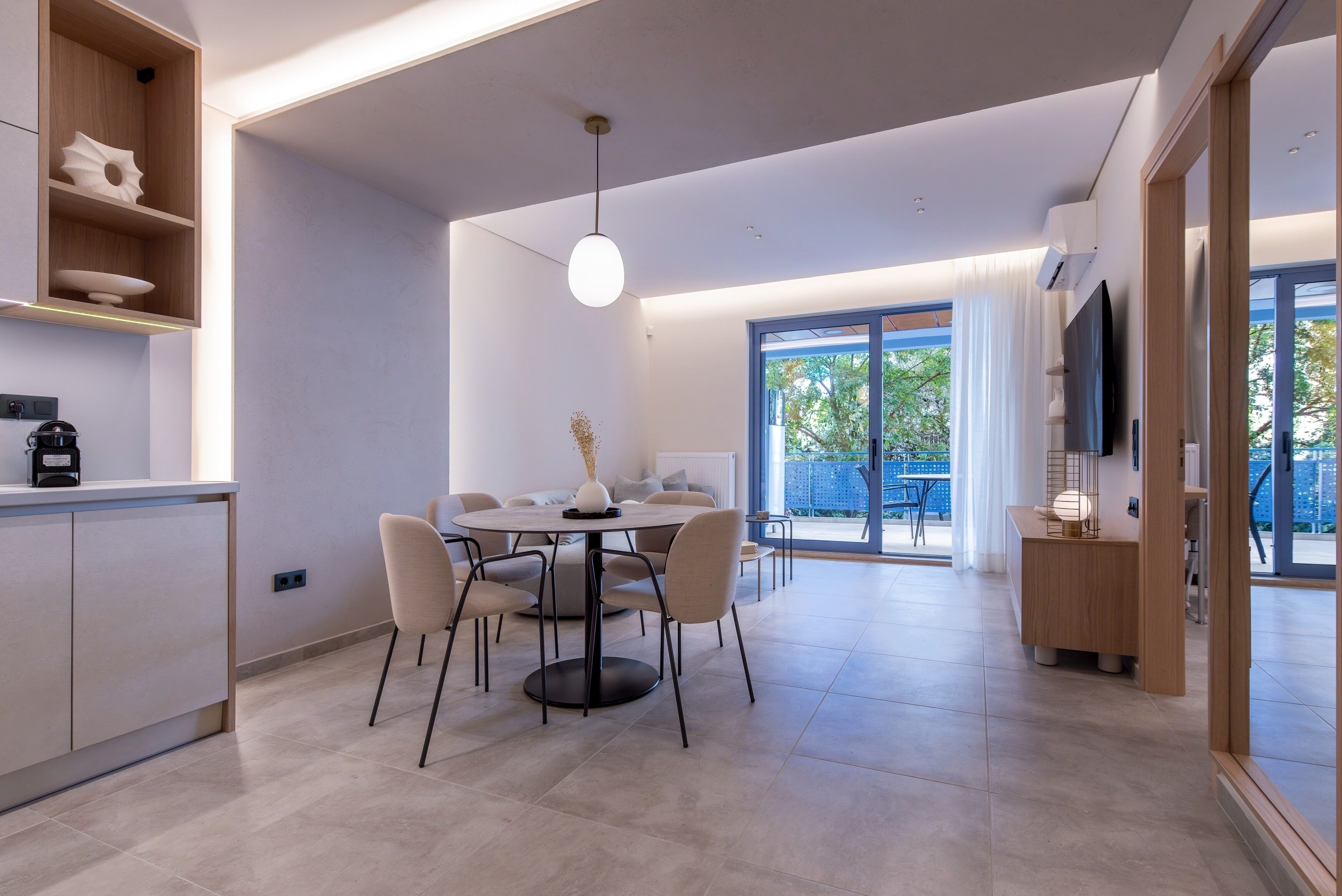 Una cocina moderna con comedor, un estante empotrado con adornos y un amplio ventanal con vistas al exterior.