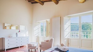 A bedroom with a bed, a chair, a dresser, and a window with a view of greenery. - Villa / Independent home in Capannori with 3 bedrooms sleeps 6 (Capannori)
