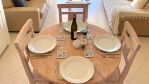 Una mesa redonda de madera para comer con cuatro platos, dos copas de vino, una botella de vino y un salero y pimentero.
