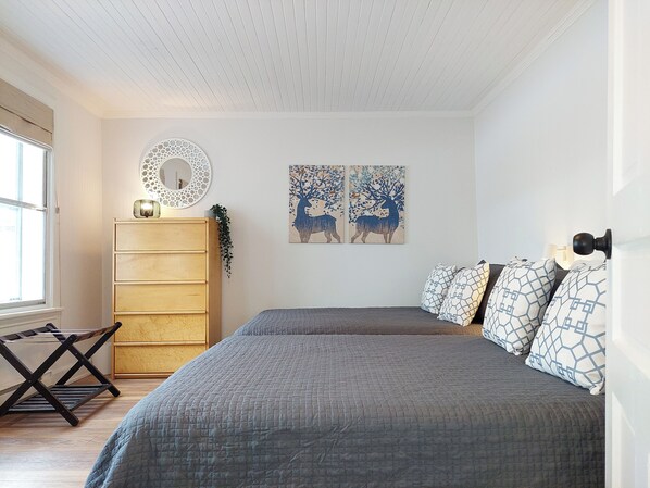 A bedroom with a bed, dresser, and artwork.