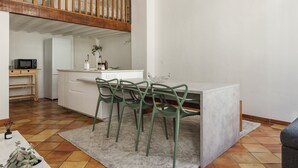 A compact kitchen with a dining area, a wooden staircase, and a small table with chairs. - L'Authentique - A Journey to Provence (Aix-en-Provence)