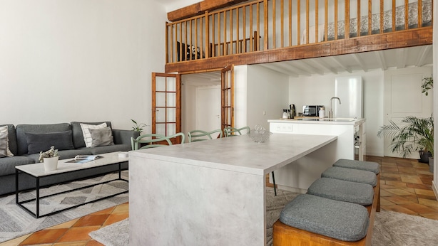 A modern living room with a sofa, coffee table, and a dining area with a table and chairs. - L'Authentique - A Journey to Provence (Aix-en-Provence)