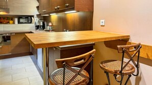 A small kitchen area with a wooden table and two wicker chairs. - Les Fables de la Fontaine (Sarlat-la-Canéda)