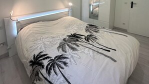 Et moderne soveværelse med seng, garderobe og spejl.