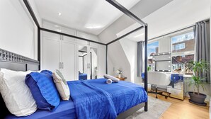 Un dormitorio moderno con una cama grande, un tocador con espejo y vistas al exterior a través de un ventanal.