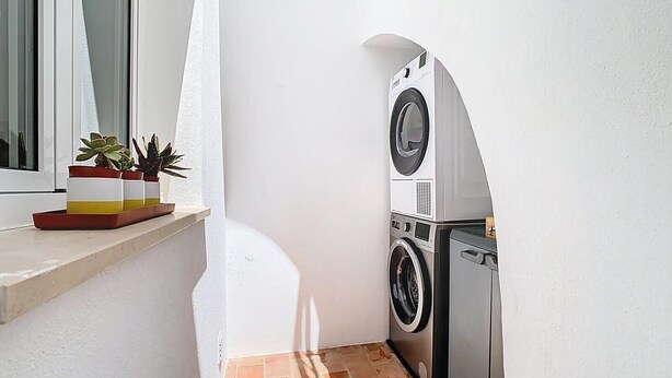 A laundry area with stacked washing machines and a window. - CASA BEIRA-MAR - Charming typical Moradia house in OLHAO -ROOFTOP and parking lot (Olhão)