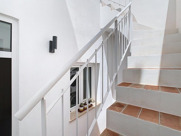 A white staircase with a metal railing leading to a window with potted plants. - CASA BEIRA-MAR - Charming typical Moradia house in OLHAO -ROOFTOP and parking lot (Olhão)