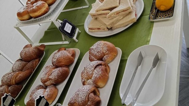Une table de buffet proposant divers plats, notamment des pâtisseries, des sandwichs et des fruits.