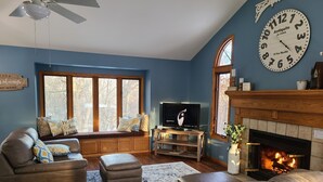 Una sala de estar con chimenea, televisor y un reloj grande en la pared.