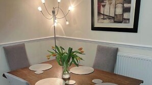 A dining table with a vase of flowers, a chandelier, and a framed artwork on the wall. - Cosy home in quiet cul-de-sac. Private fenced garden and free parking. (Wolverhampton)