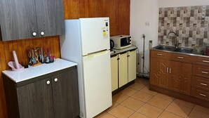 A compact kitchen with a refrigerator, microwave, and wooden cabinets.