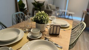 Una mesa de comedor dispuesta con platos, tazones, cubiertos, una copa, una vela y una pequeña planta en maceta.