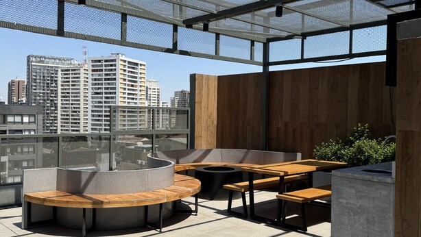Un área de estar al aire libre con mobiliario moderno y vistas a la ciudad.