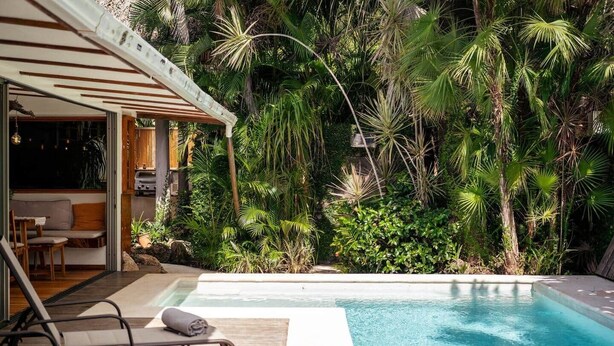 A pool area with lounge chairs and a covered seating area, surrounded by dense tropical vegetation. - Private villa only a short stroll to the beach/Organic shop (Cobano)