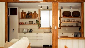 A compact kitchen with white cabinets, wooden shelves, and a window. - Private villa only a short stroll to the beach/Organic shop (Cobano)