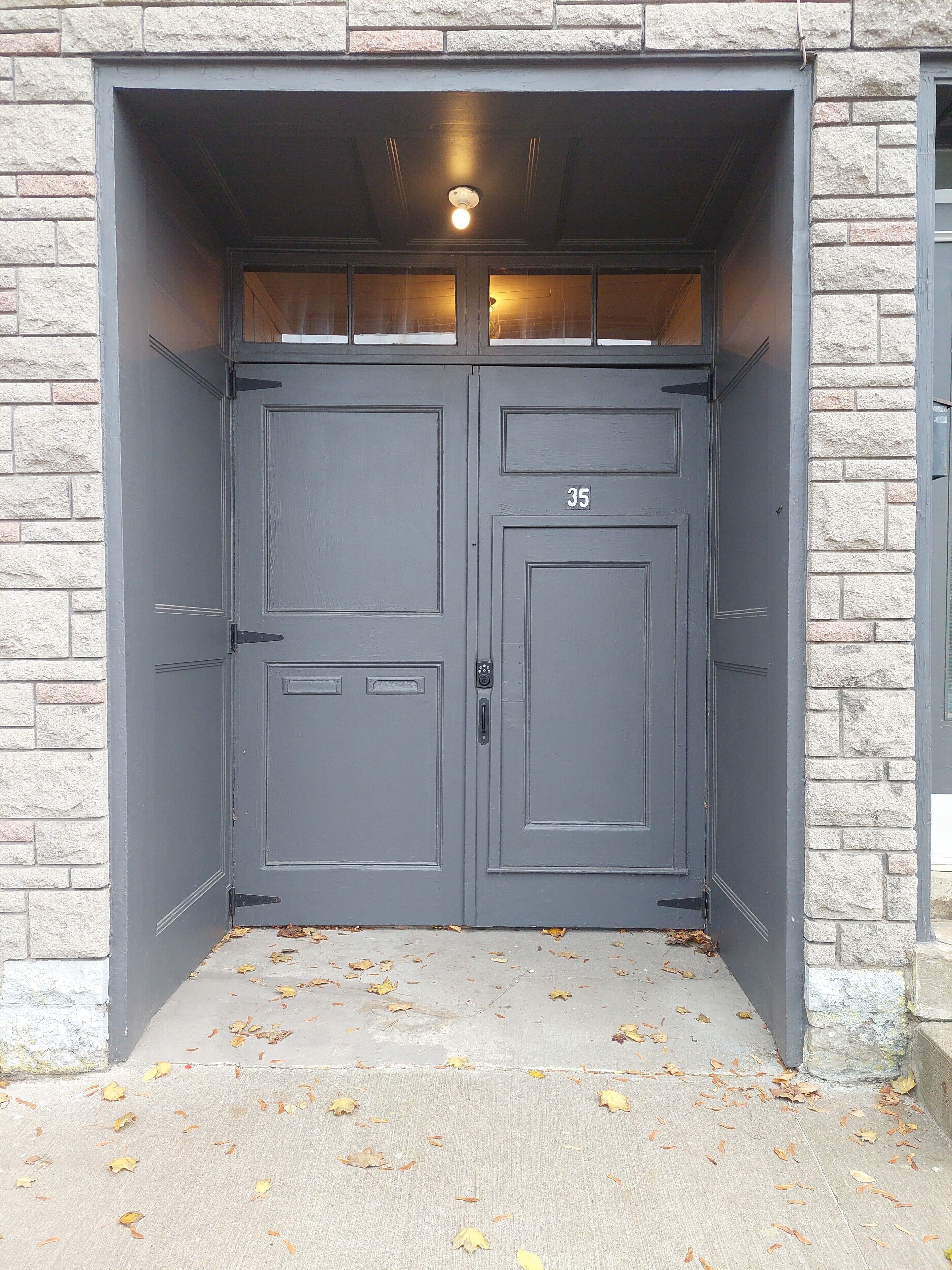 A double door with a number plate '35' and a keypad lock, set in a stone wall.