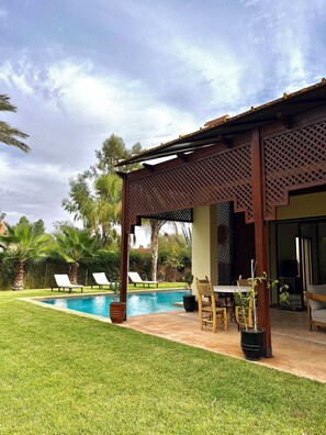 A pool area with a pergola, lounge chairs, and a dining table. - Fabulous Family Villa in Marrakesh (Marrakech)