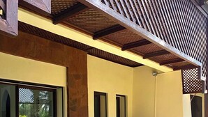 A covered outdoor seating area with a table and chairs, a sofa with cushions, and a cat near the entrance. - Fabulous family villa in Marrakech (Marrakech)