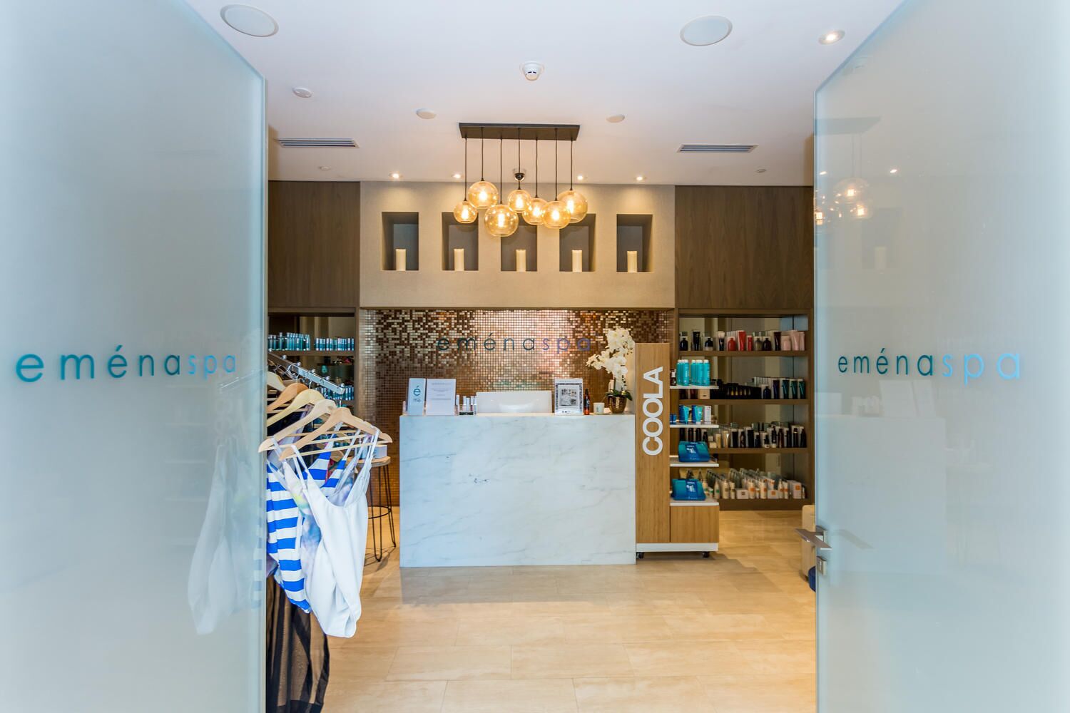 Un spa moderne doté d’un comptoir d’accueil, d’étagères remplies de produits et d’un portant à vêtements.