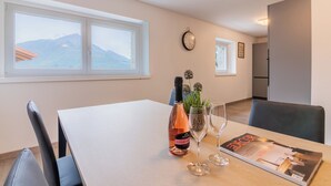 A dining area with a table set for two, a bottle of wine, a glass, and a magazine.