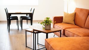 A modern living room with a wooden table, a sofa, and a dining area with chairs.