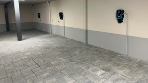 A parking garage with tiled floors and walls, equipped with electric vehicle charging stations.