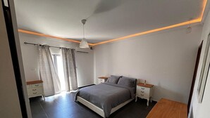 A bedroom with a bed, bedside tables, a ceiling light, and a window with curtains. - Naxxar 3-Bedroom Spacious Family Home with Private Roof by Malta Weekend (Naxxar)