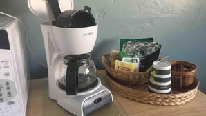 A coffee maker on a kitchen counter with a basket containing Lipton tea bags and a mug.