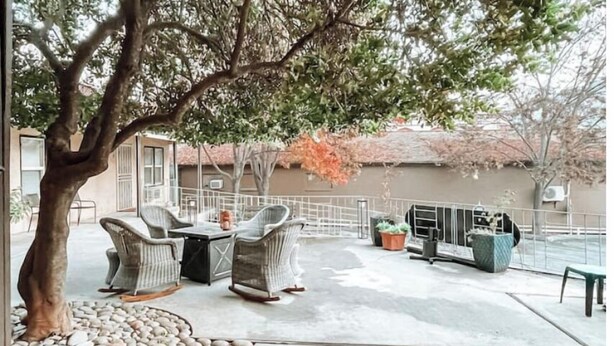 An outdoor patio with wicker furniture, a tree, and a railing.