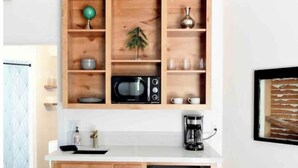A compact kitchen with a microwave, coffee maker, and a small refrigerator.
