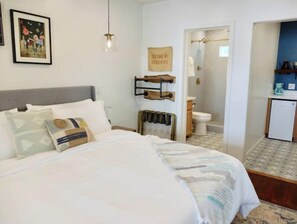Ein Schlafzimmer mit Bett, Nachttisch, Pendelleuchte, einem gerahmten Bild an der Wand und einem Schild mit der Aufschrift 'YOU ARE MY SUNSHINE'.