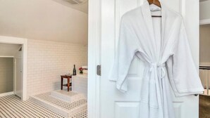A white bathroom with a tiled floor, a small table with a bottle, and a wooden stool. - Romantic King Room Near Calistoga Spa & Hot Springs. (Calistoga)