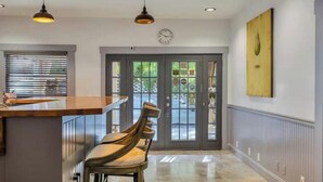 A kitchen with a wooden countertop, a bar area, and a dining chair. There is a clock on the wall and a door leading outside. - Romantic King Room Near Calistoga Spa & Hot Springs. (Calistoga)